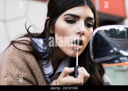 Porträt der jungen Frau Anwendung Lippenstift draußen Stockfoto