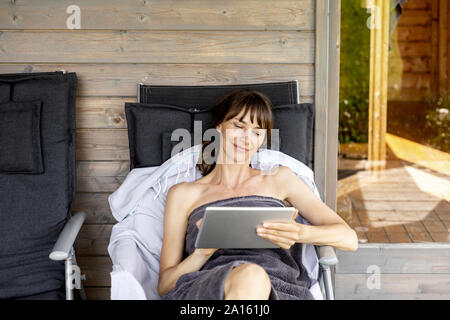 Frau Entspannung auf eine Lounge im Freien Sauna mit Tablet Stockfoto