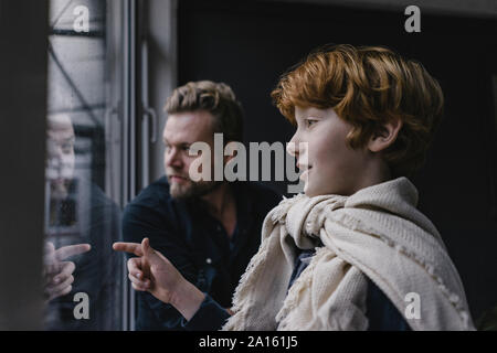 Junge und sein Vater auf der Suche aus dem Fenster Stockfoto