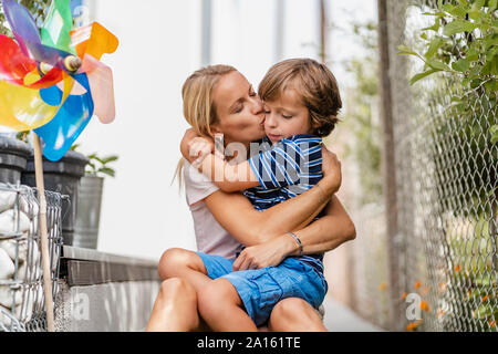 Mutter und Sohn umarmen und küssen im Garten Stockfoto