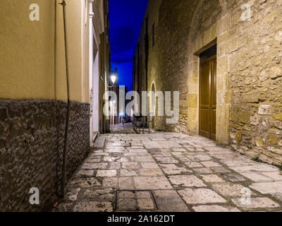 Beleuchtete leere Gasse inmitten von Gebäuden in der Altstadt bei Nacht Stockfoto