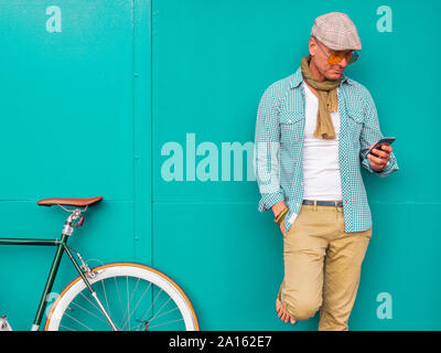 Mann mit Fixie bike stand vor der grünen Wand an Zelle Telefon Stockfoto