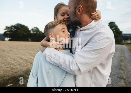 Liebevoller Vater mit zwei Kindern im Freien Stockfoto