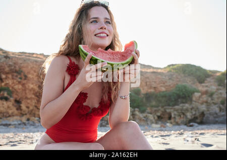 Glückliche junge Frau mit Wassermelone Schicht am Strand Stockfoto