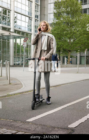 Junge Frauen reiten Elektroroller auf der Straße Stockfoto