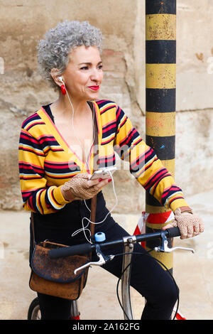 Portrait von durchbohrt, reife Frau mit Fahrrad Musik hören mit earphobnes und Handy Stockfoto