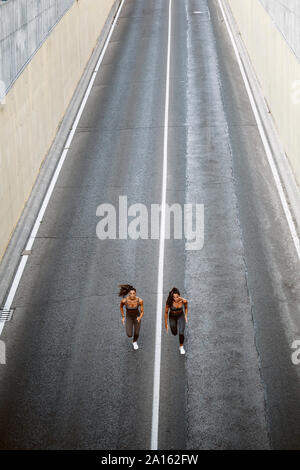 Blick von oben auf die beiden sportlichen Zwillingsschwestern, die auf einer Straße Stockfoto