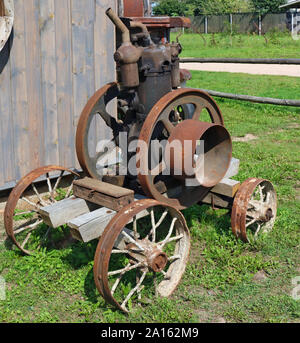 Rusty vintage kleine Traktoren Diesel Motor in der Nähe des ländlichen Scheune vergessen Schuppen. Die Ausstattung ist mehr als vor hundert Jahren. Masse pro Stockfoto