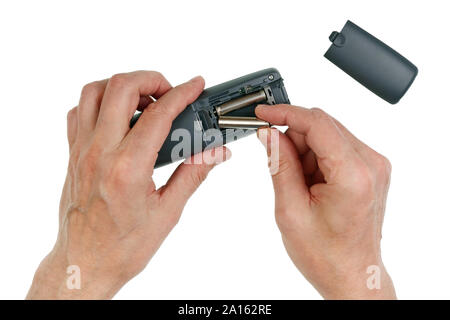 Ältere ältere Mann fügt Batterien in ein schnurloses Telefon zuhause Hörer. Auf weissem studio Konzept isoliert Stockfoto