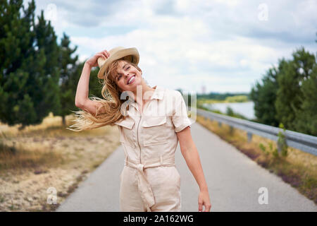 Lächelnde Frau auf die ländliche Straße am See Stockfoto