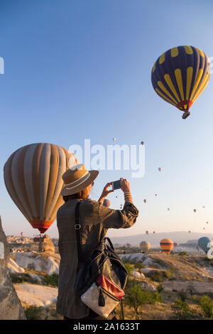 Junge Frau und Heißluft-ballons, Göreme, Kappadokien, Türkei Stockfoto