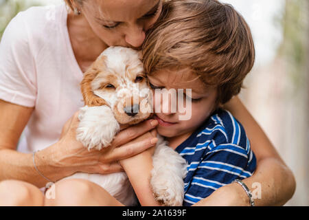 Mutter und Sohn Kuscheln mit niedlichen Hund Welpe Stockfoto