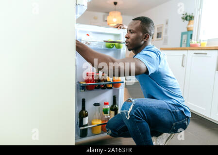 Junge Mann in den Kühlschrank in der Küche zu Hause suchen Stockfoto