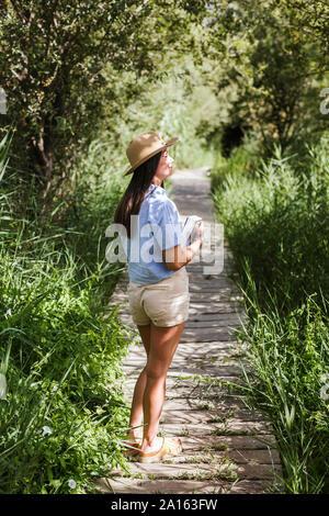 Junge Frau mit Buch auf Holzsteg Stockfoto