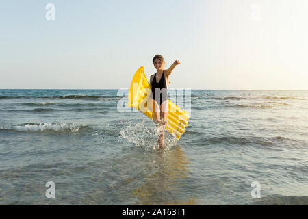 Junge Frau mit gelb Luftmatratze am Strand Stockfoto