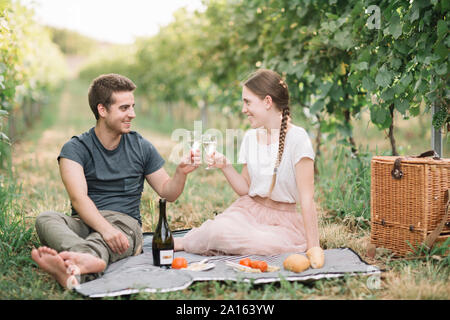 Glückliches junges Paar mit Picknick in den Weinbergen, Toasten mit Prosecco Stockfoto