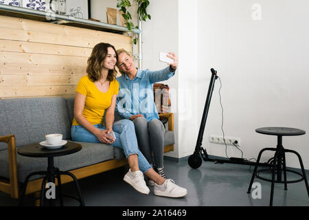 Freunde unter selfies in einem Café, e-Scooter, laden im Hintergrund Stockfoto