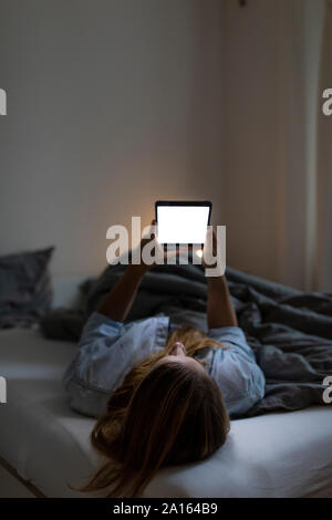 Junge Frau im Bett zu Hause in der Nacht mit Tablet Stockfoto