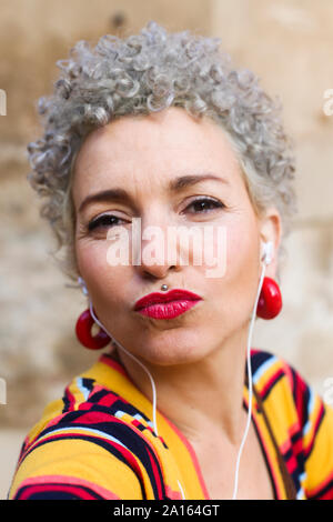 Portrait von durchbohrt, reife Frau mit grauen lockiges Haar schmollend Mund Stockfoto