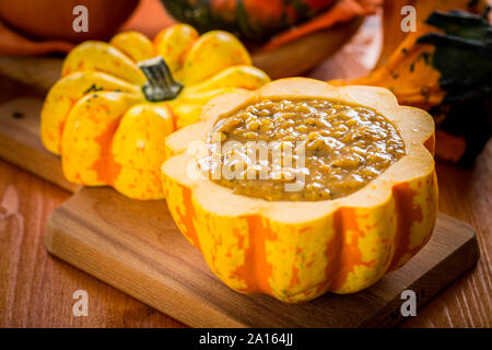 Rote Linsen Suppe mit Kürbisse in ausgehöhlten Kürbis serviert. Stockfoto