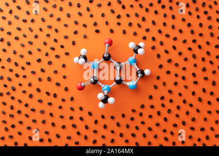 Direkt über der Ansicht von Koffein chemische Formel mit gerösteten Kaffeebohnen über orange Hintergrund Stockfoto