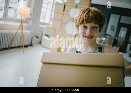 Portrait von lächelnden rothaarigen Jungen mit Karton Stockfoto