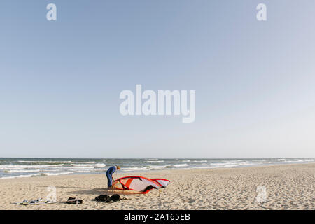 Männliche surfer Vorbereiten eines Drachen am Strand Stockfoto