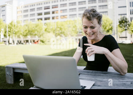 Portrait von lächelnden reife Geschäftsfrau mit Laptop und Kaffee im Freien zu gehen Stockfoto