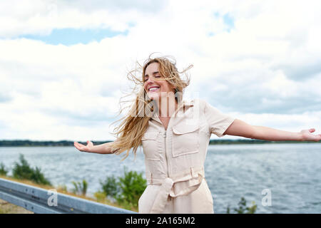 Glückliche Frau an der Lakeside mit ausgestreckten Armen Stockfoto