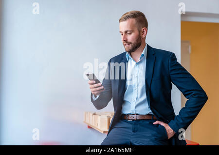 Geschäftsmann mit Handy im Büro Stockfoto