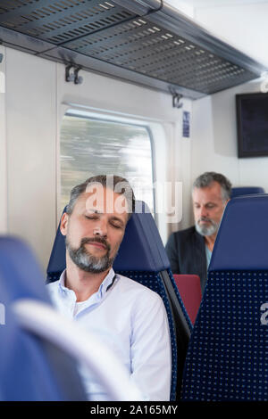 Reifer Mann im Zug sitzen, schlafen Stockfoto