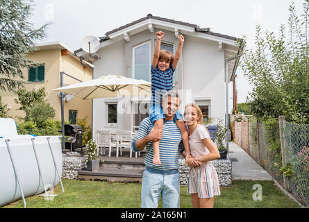 Portrait von Vater mit Frau Sohn auf den Schultern im Garten Stockfoto