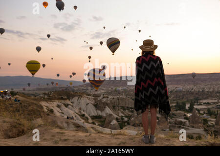 Junge Frau und Heißluftballons am Abend, Göreme, Kappadokien, Türkei Stockfoto