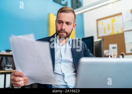 Geschäftsmann mit Papieren am Schreibtisch im Büro Stockfoto