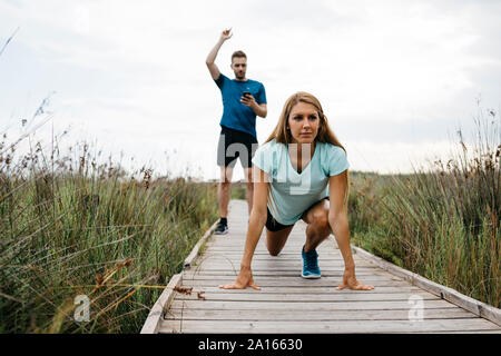 Weibliche Jogger mit Ihrem Trainer auf einem Holzsteg Stockfoto