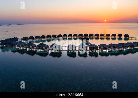 Malediven, Insel Olhuveli, Resort Bungalows auf Süd Male Atoll Lagune bei Sonnenuntergang Stockfoto