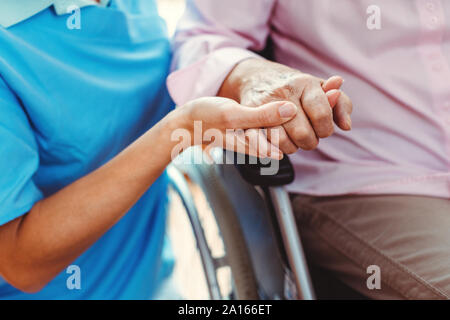 Krankenschwester, tröstliche eine ältere Frau im Pflegeheim ihre Hand in das Pflegeheim Holding Stockfoto