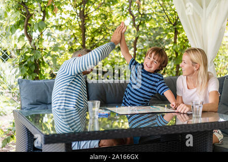 Gerne Vater und Sohn hohe Fiving, nachdem er ein Spiel auf der Terrasse Stockfoto