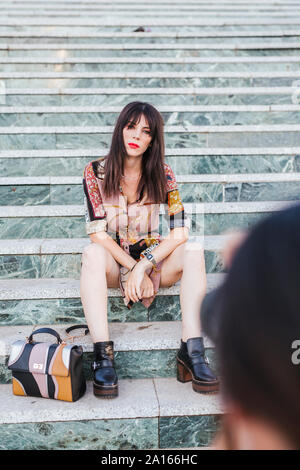 Junge Frau mit gemusterten Kleid für ein Fotoshooting auf der Treppe posiert Stockfoto