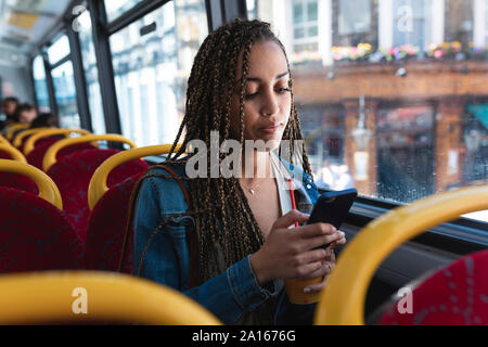 Porträt der jungen Frau im Bus am Handy, London, Sitzen, Großbritannien Stockfoto