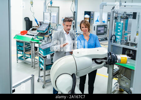 Geschäftsmann mit Tablet und Frau sprechen bei der Montage Roboter in einer Fabrik Stockfoto