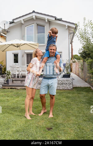 Portrait von Vater mit Frau Sohn auf den Schultern im Garten Stockfoto