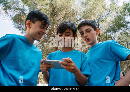 Drei Männer in blauen T-Shirts mit Smartphone Stockfoto