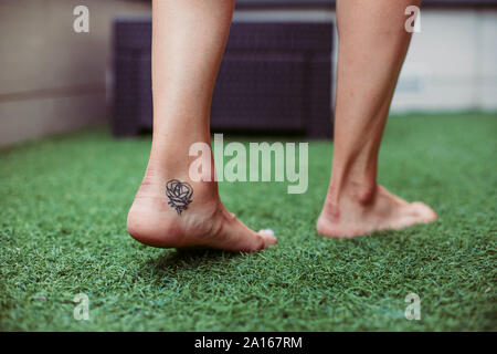 Nahaufnahme von einer Frau tätowiert Fuß zu Fuß auf Kunstrasen Stockfoto