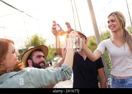 Gruppe von Freunden Toasten mit Flaschen Bier im Gewächshaus Stockfoto