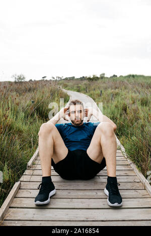 Jogger, Sit-ups auf einem Holzsteg Stockfoto