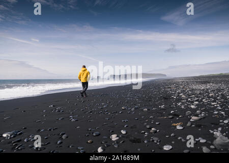 Reifer Mann zu Fuß auf einer Lava Strand in Island Stockfoto