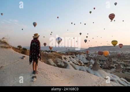 Junge Frau und Heißluftballons am Abend, Göreme, Kappadokien, Türkei Stockfoto