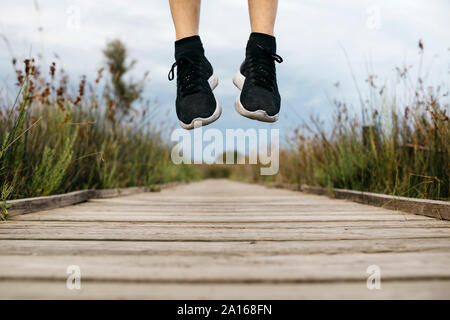 Schwarz Laufschuhe, männliche Jogger springen auf einem Holzsteg Stockfoto