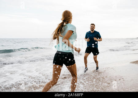 Junges Paar am Strand joggen Stockfoto